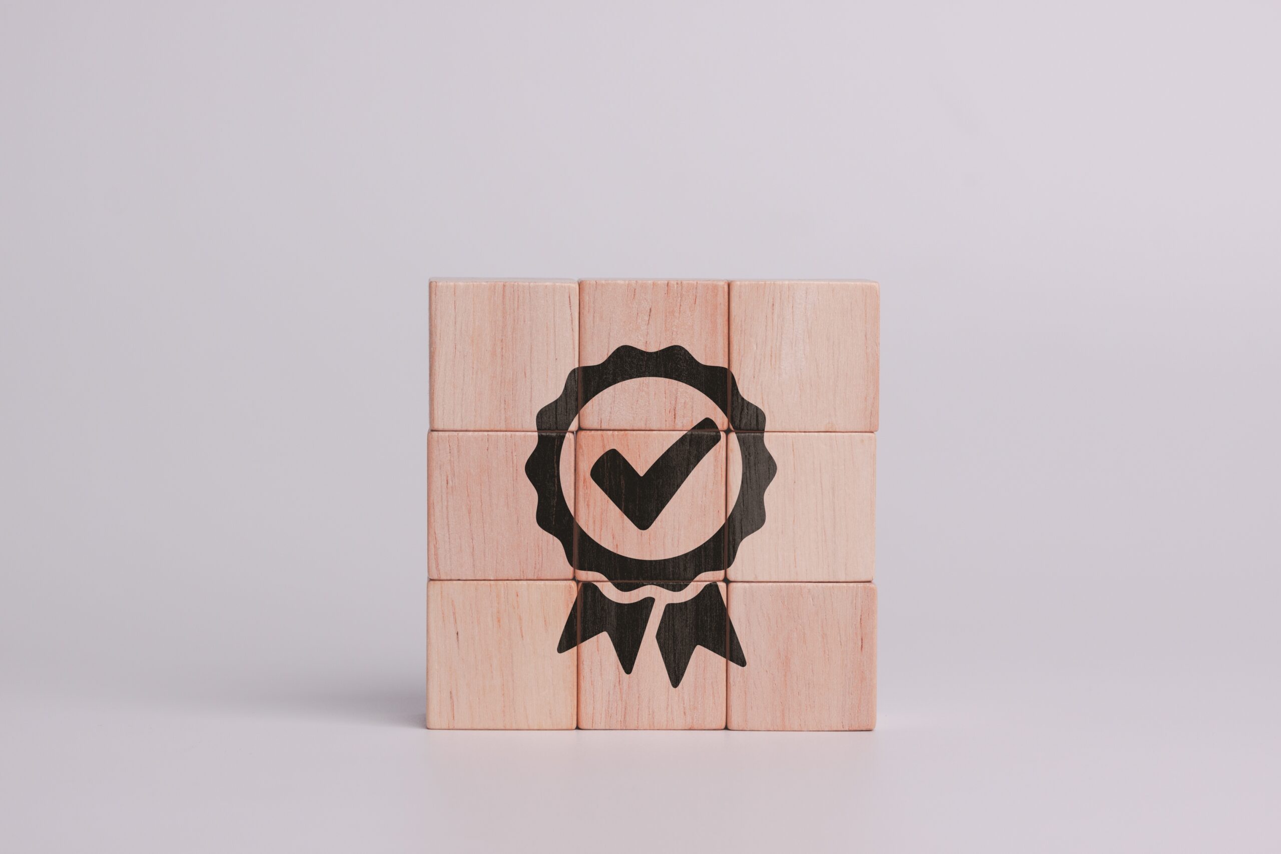 inopla Technlologie Garantie: Auszeichnung auf Holzwürfel mit grauem Hintergrund